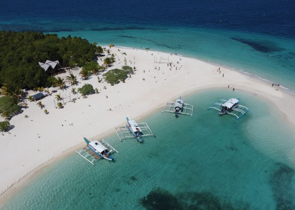 Drone shot over white sand beach blue water of Balabac
