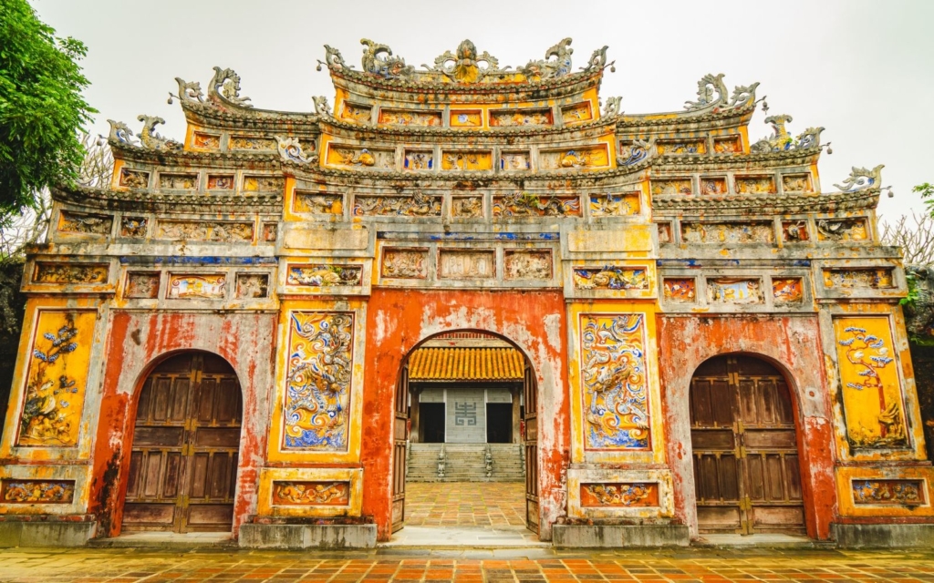 Ancient gate in the Hue with red and yellow paint and reliefs