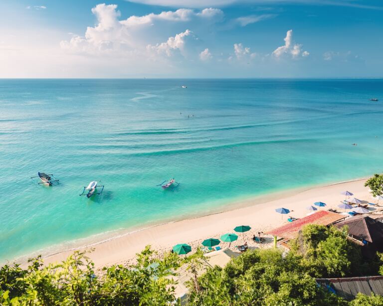 Tropical blue ocean, sandy beach and boats in Indonesia, Bali.