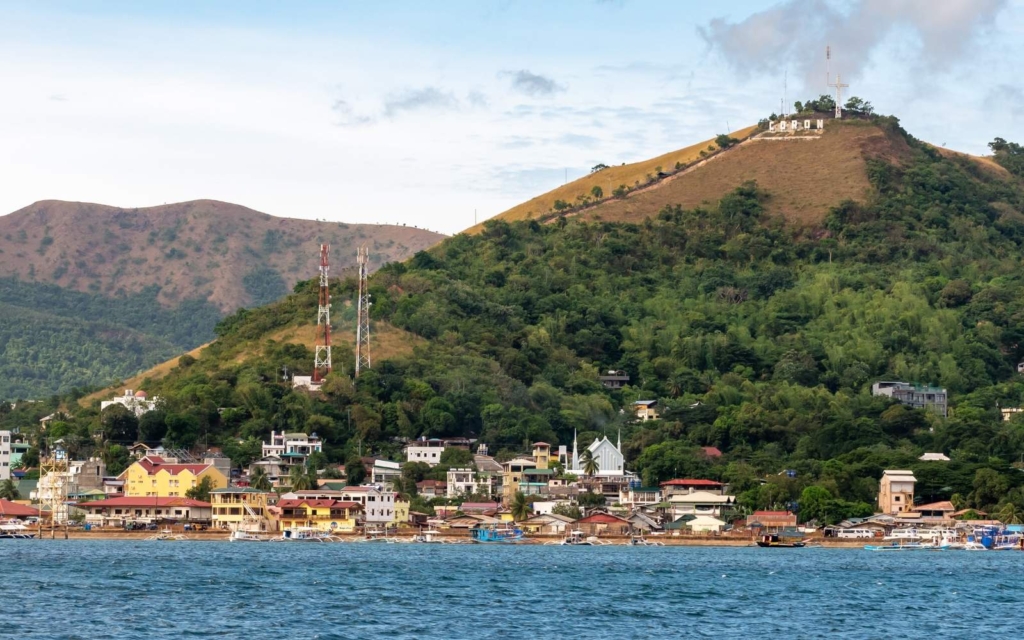 Blue water with Coron town in the background with mountains