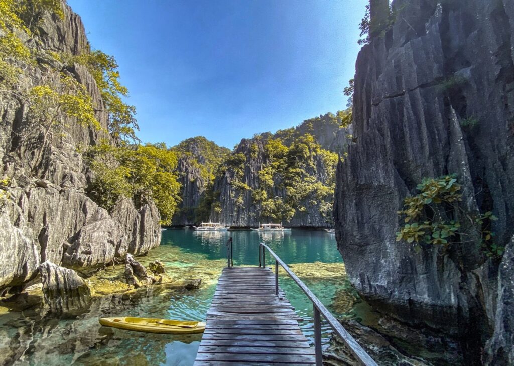 Wooden walkway and kayak in Coron lagoon surrounded by rocky crags