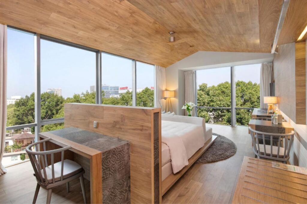 Bright open hotel room with natural light and wooden ceilings at Fusion Suites Saigon