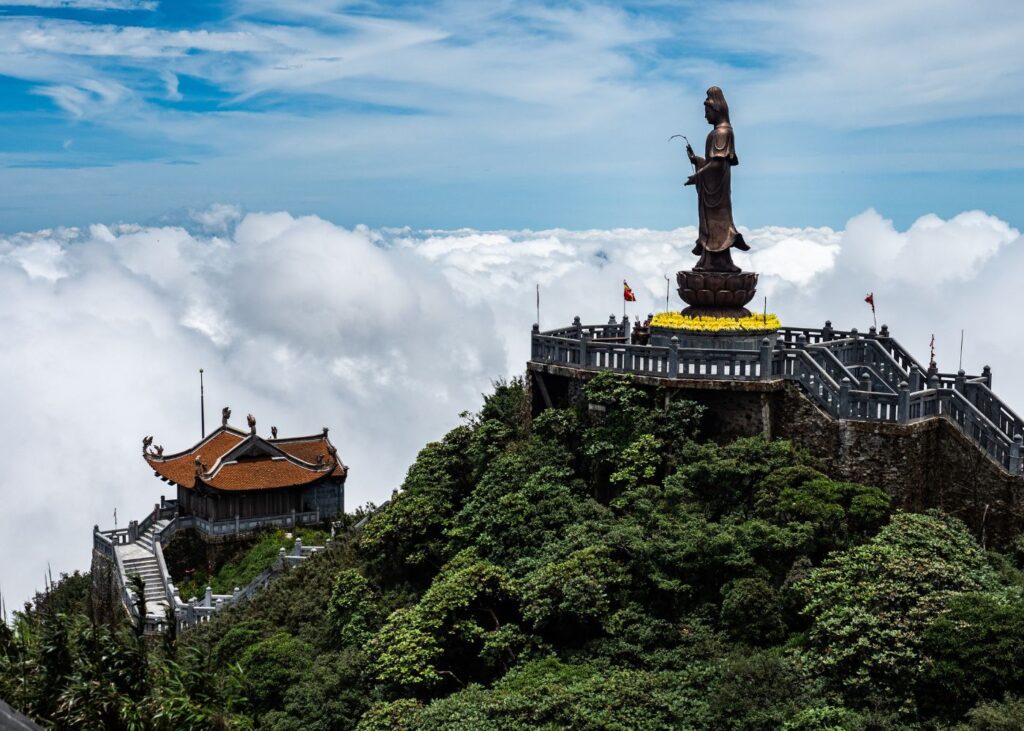 Buddha statue with clouds and a pagoda on top of Fansipan Mountain in Sapa Vietnam