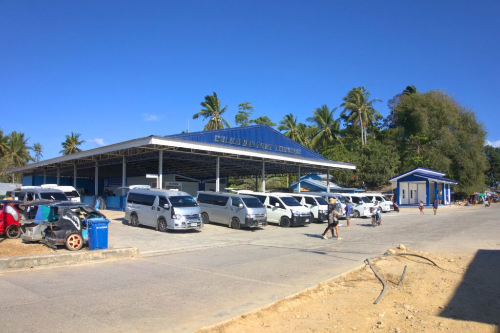 Buliluyan public ferry port on Palawan mainland with tourist vans and people walking