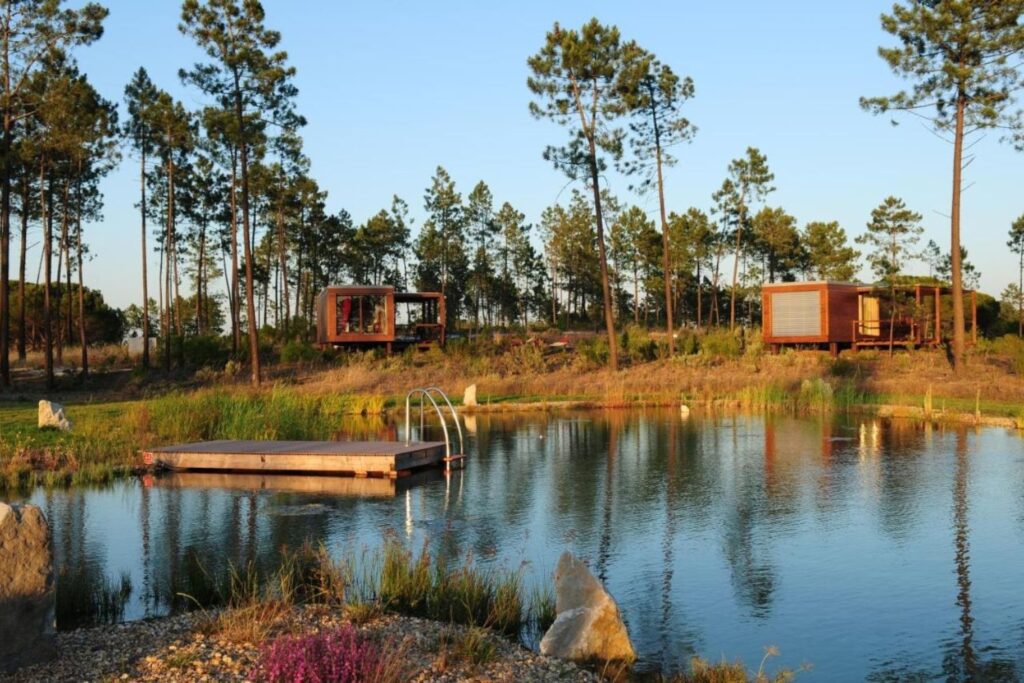 bungalows surrounded by trees, nature, and a lake at the front