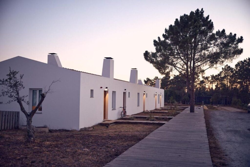 view of a white country house surrounded by trees and nature at sunset