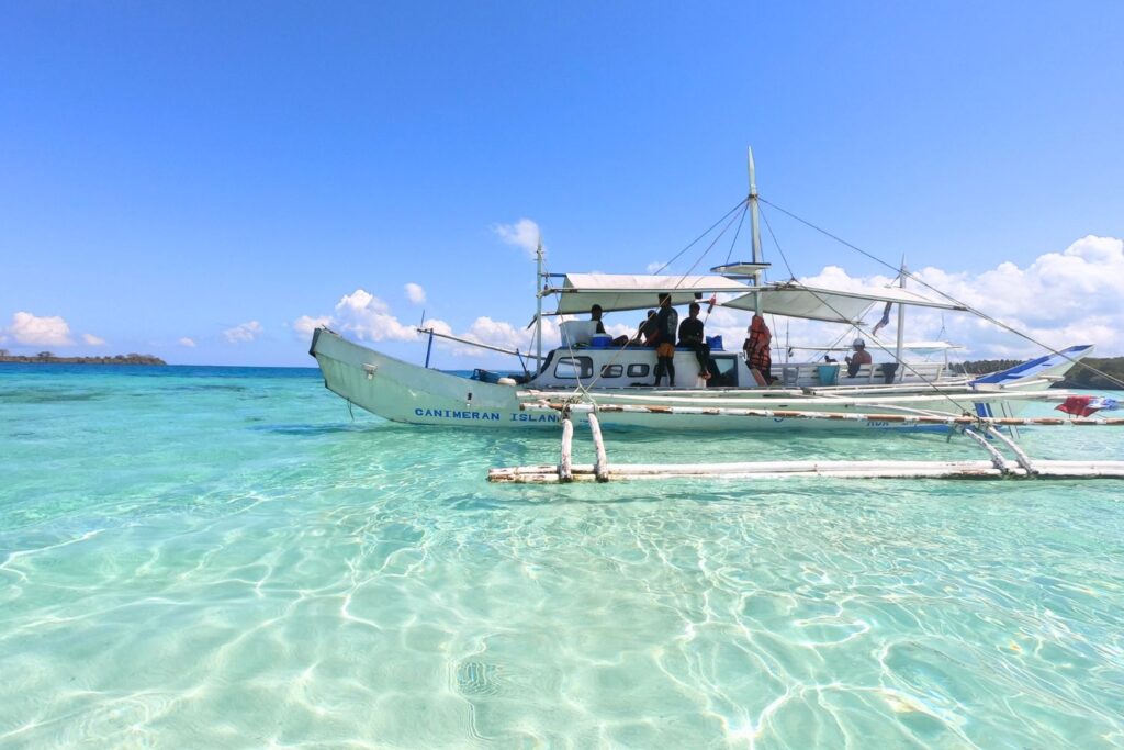 Filipino boat with stabilizers on clear water with crew