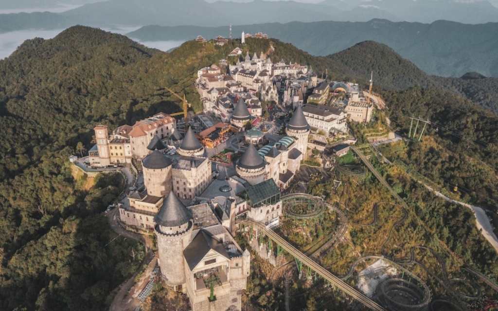 French chateau towers of Sun World Ba Na Hills amusement park near Da Nang, Vietnam with mountains in the background