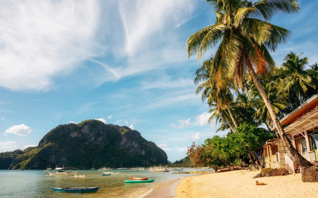 Golden sands, palm trees, and beach hotels at Corong Corong Beach, one of the best places to stay in El Nido Palawan