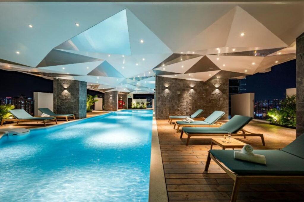 Indoor pool area with modern geometric ceiling and lounge chairs at Amanaki Suites