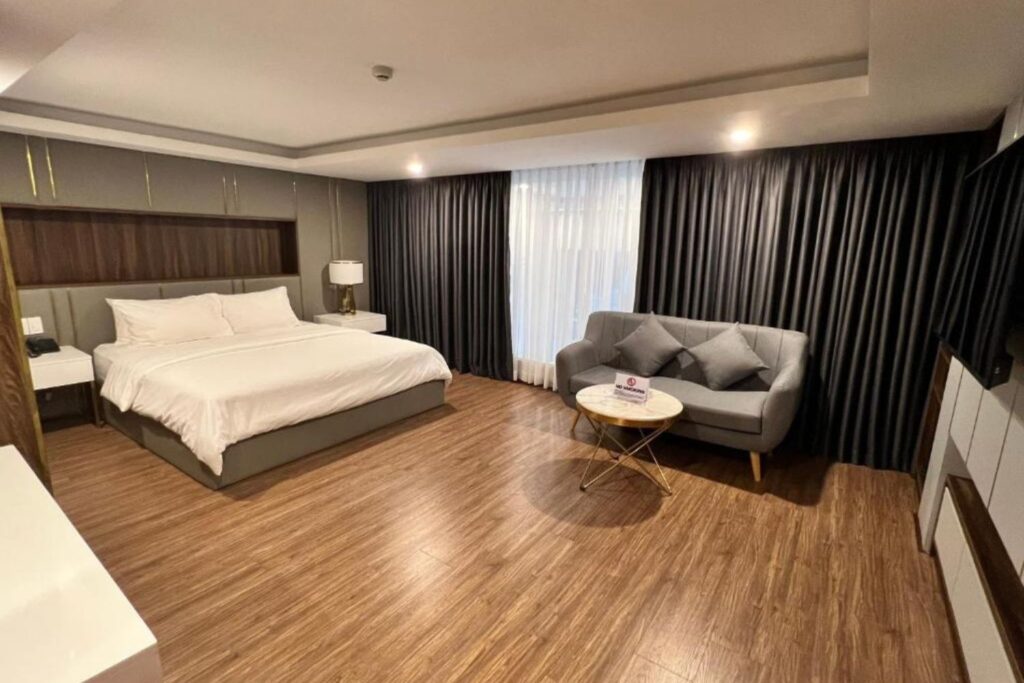 King room with dark curtains and wooden floors at Nam Hy Hotel