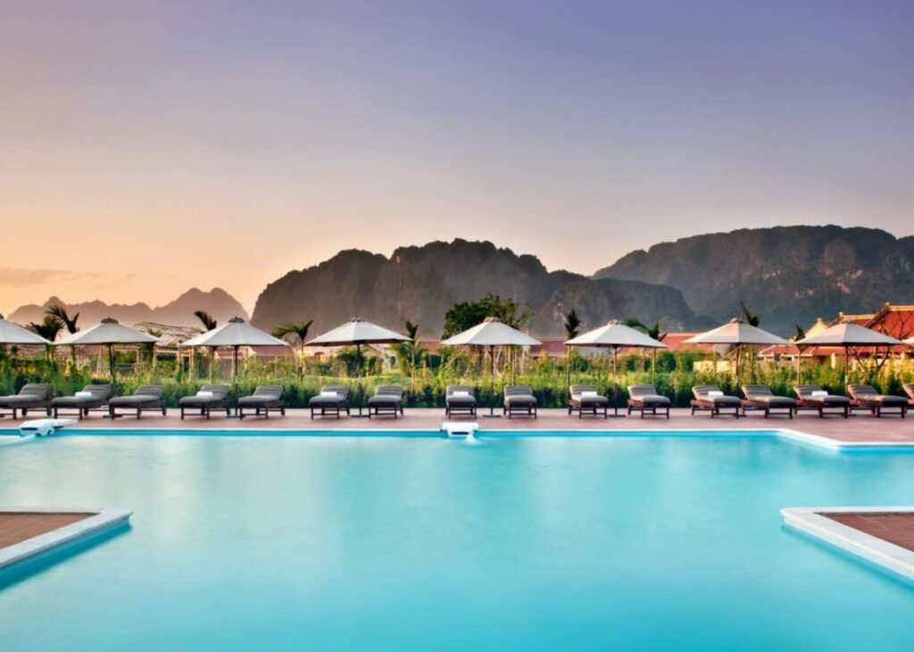 Large blue swimming pool with loungers and mountains in the background