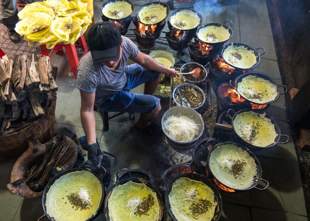 Man cooking ban xeo in Vietnam in a street market