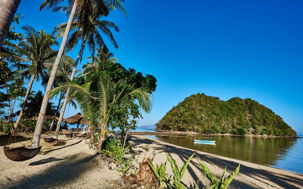 
Marimegmeg Beach with palm trees, limestone bluff, and tiki huts.