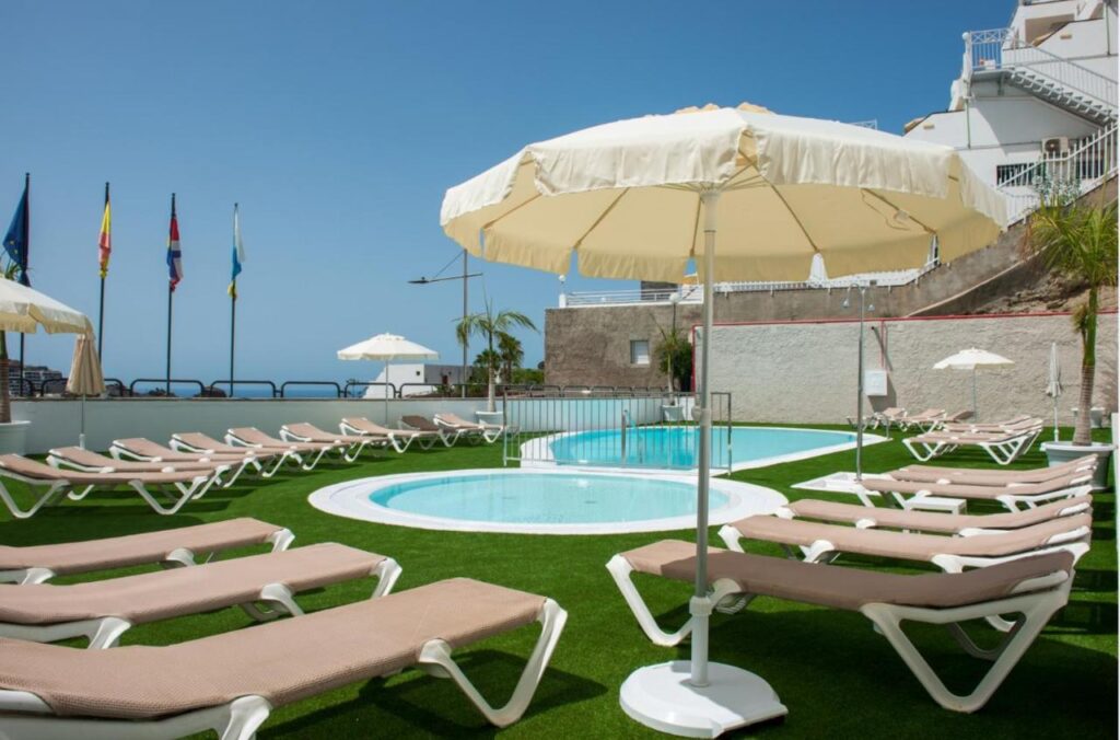 small outdoor pool with sun loungers and umbrella