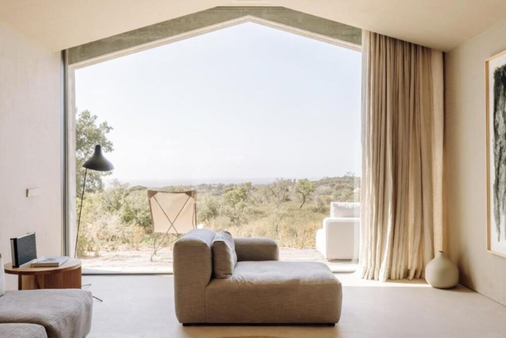 spacious living room with wide glass window and nature view