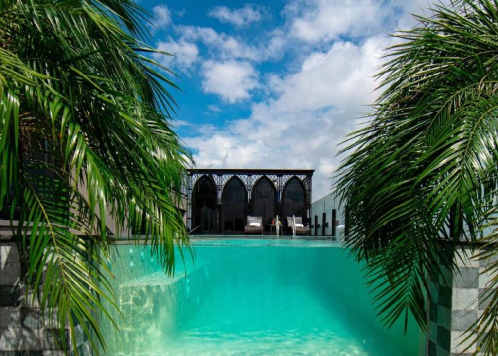 pool at Le Chanvre Hanoi Hotel & Spa with palm trees and blue water