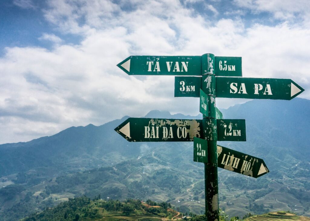 Road sign in North Vietnam with arrows and mountains in the background