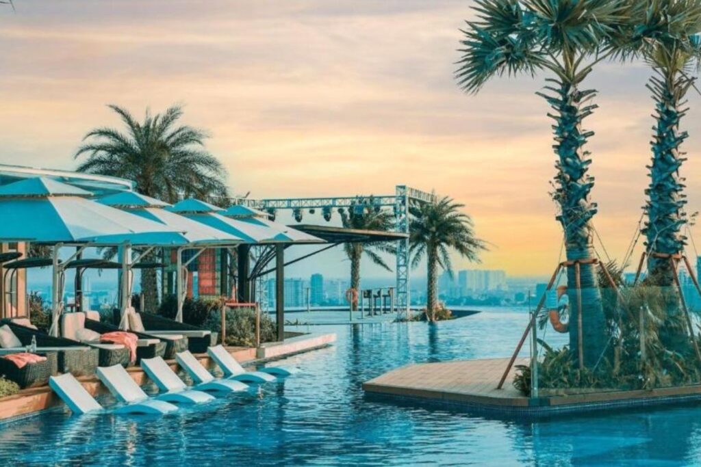 Rooftop pool area of La Vela Saigon in Ho Chi Minh with lounge chairs and palm trees