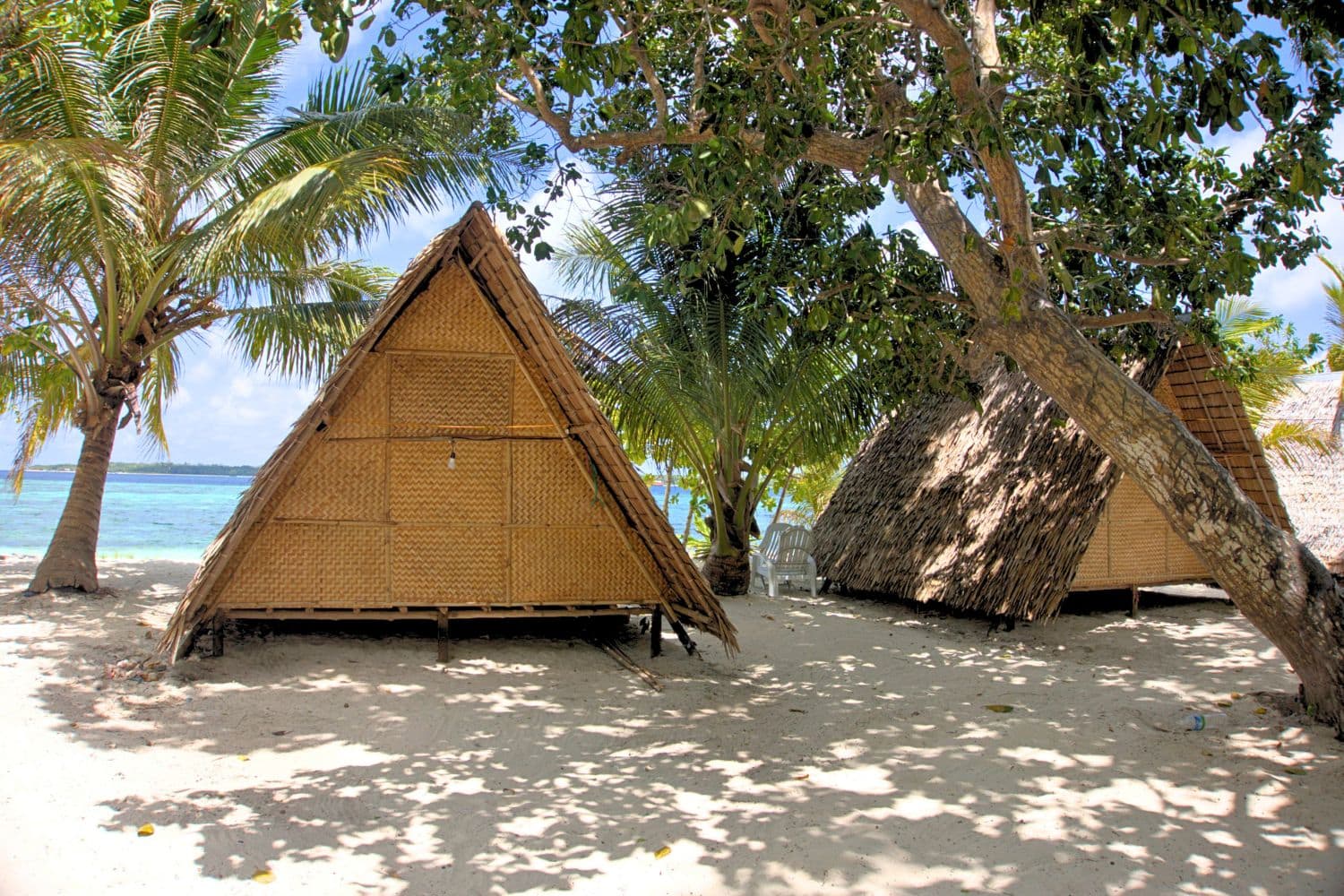 Thatched roof huts under palm trees in Balabac