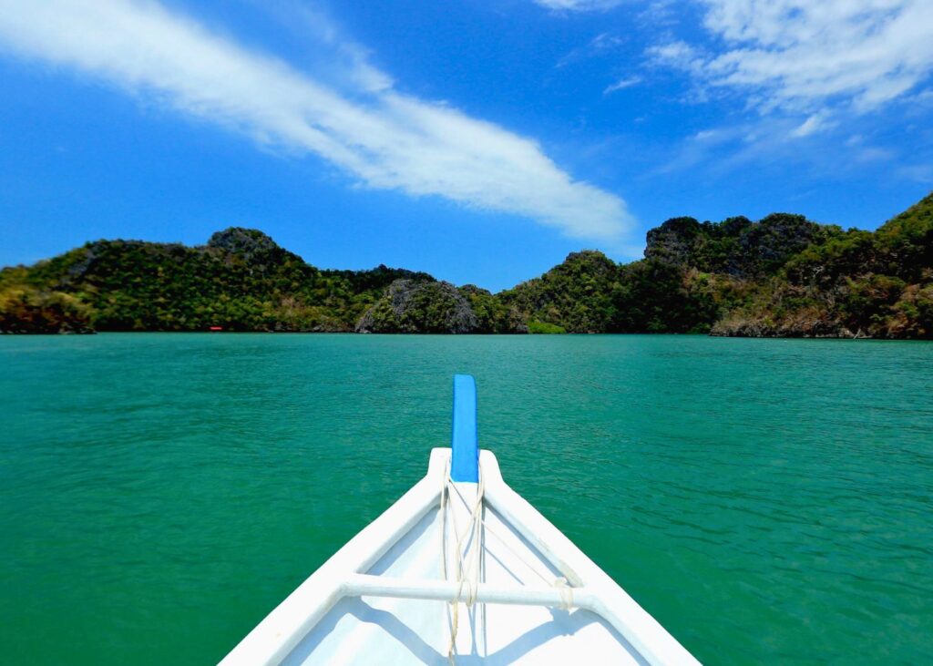 Traditional boat approaching Langkawi Island with green water and mountains