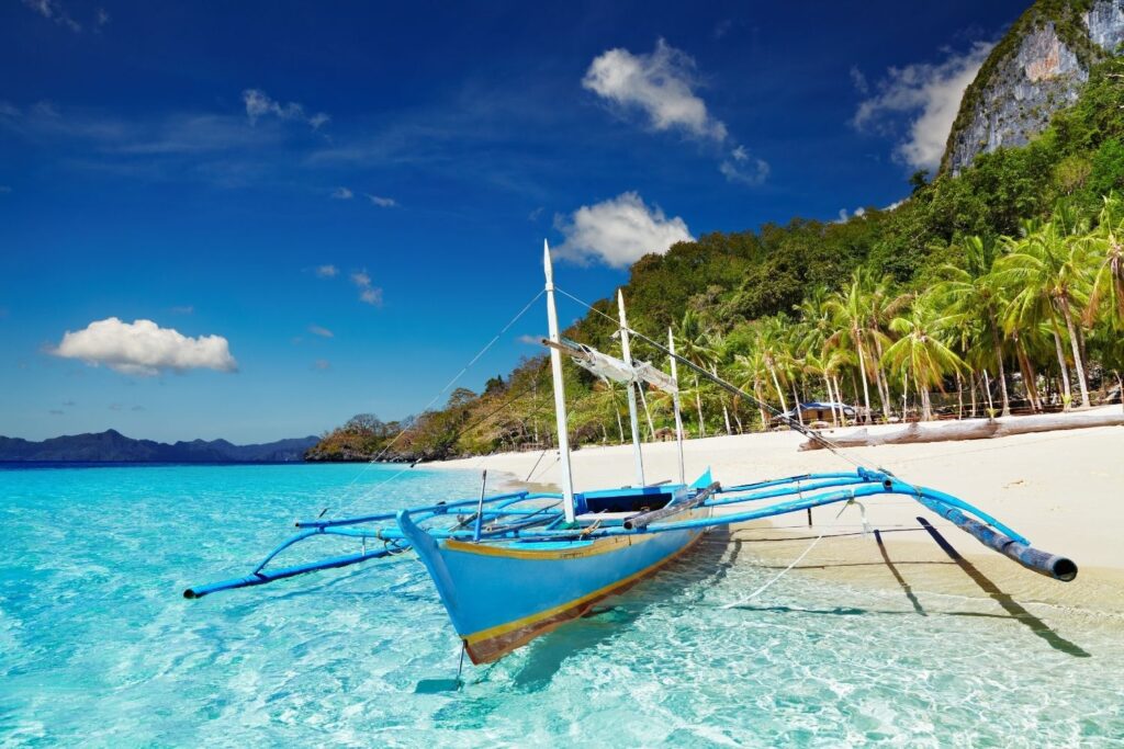 Traditional Philippine boat in clear water with palm trees in the background