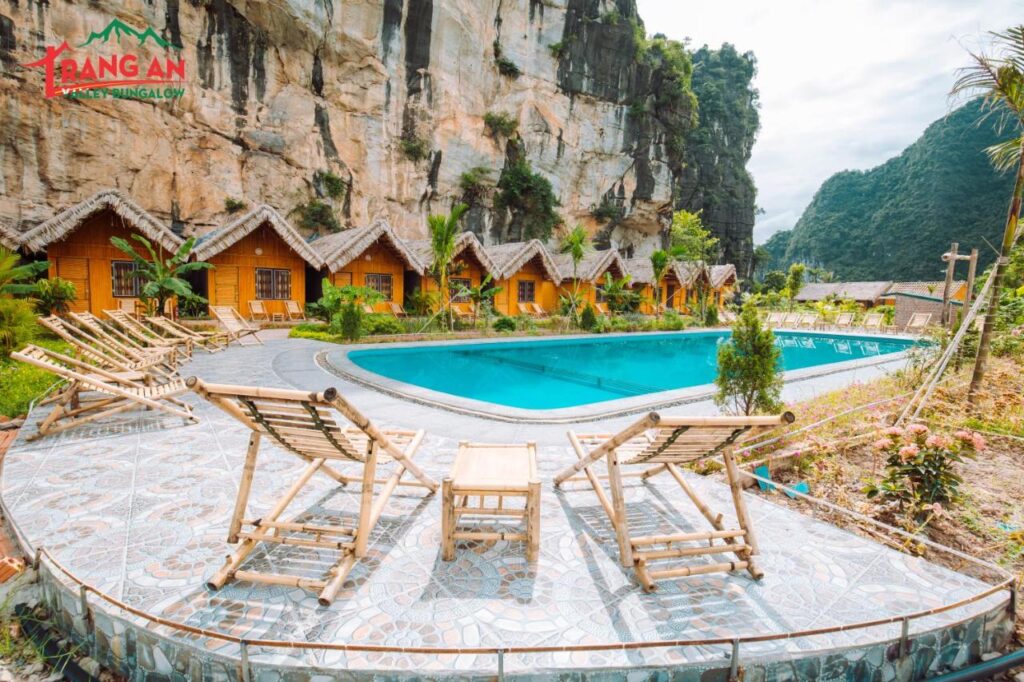 pool view with bamboo chairs and traditional huts at Trang An Valley Bungalow