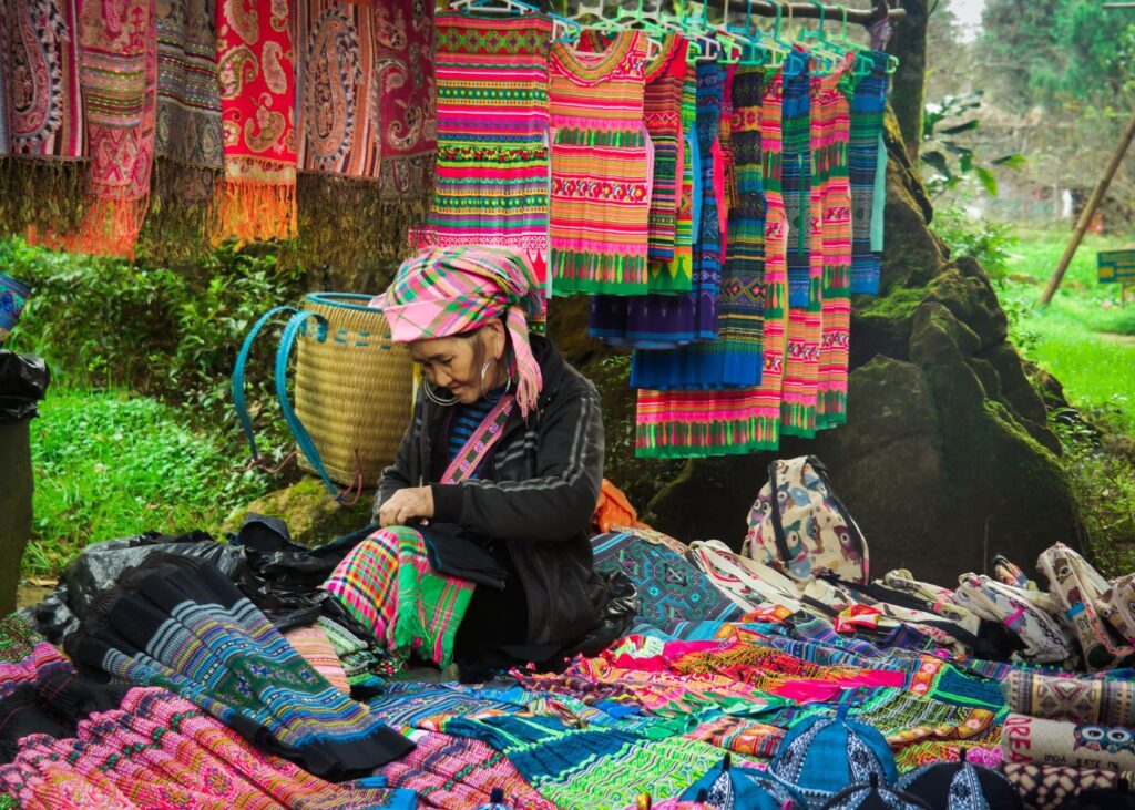Vietnamese village woman folding traditional clothing in a fabric shop