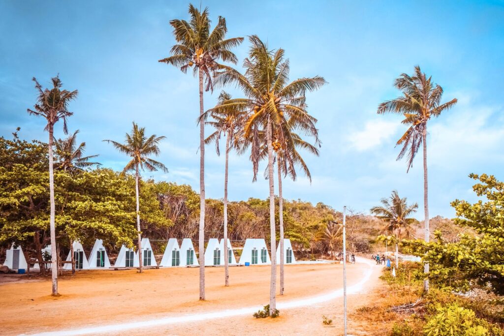 White teepee huts amidst palm trees with blue sky in Philippines