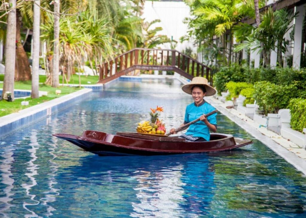 Woman in traditional Thai boat delivering food on a water canal