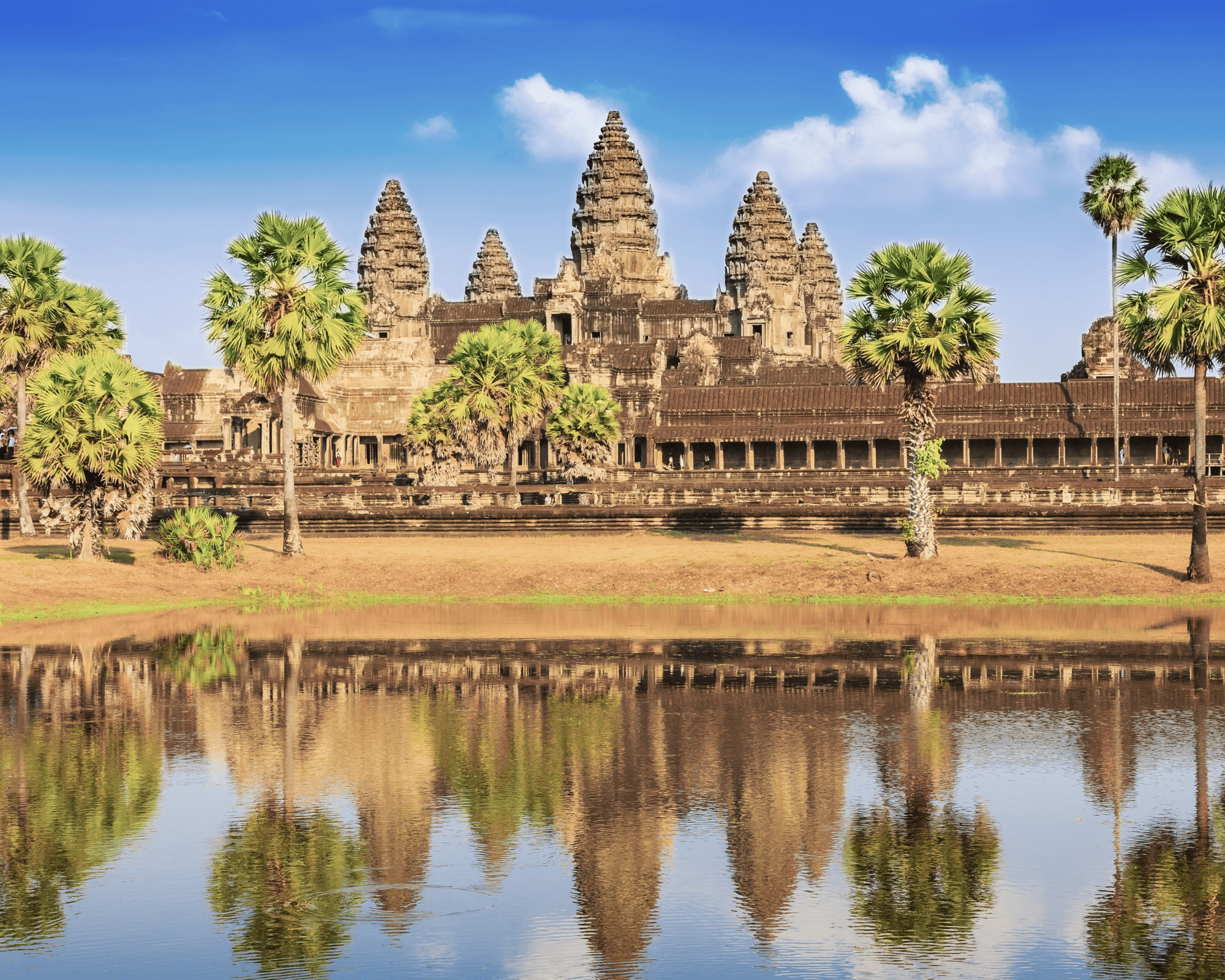 Angkor Wat with water in front and a blue sky with clouds