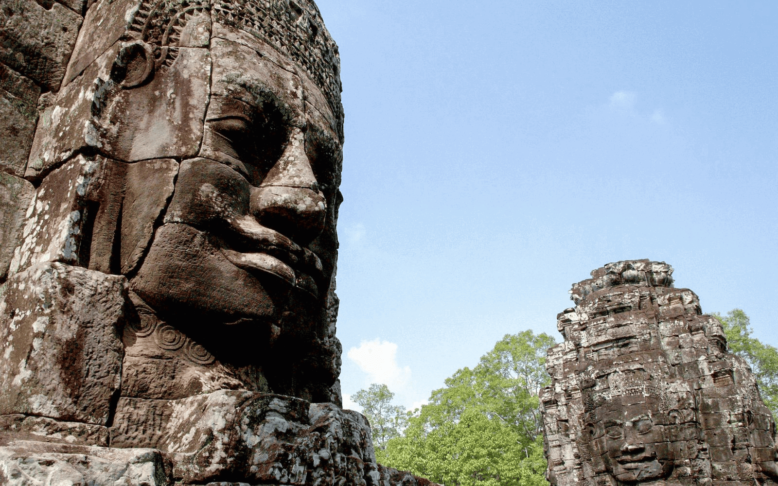 Stone face statues of Bayon Temples at Angkor Thom against a blue sky